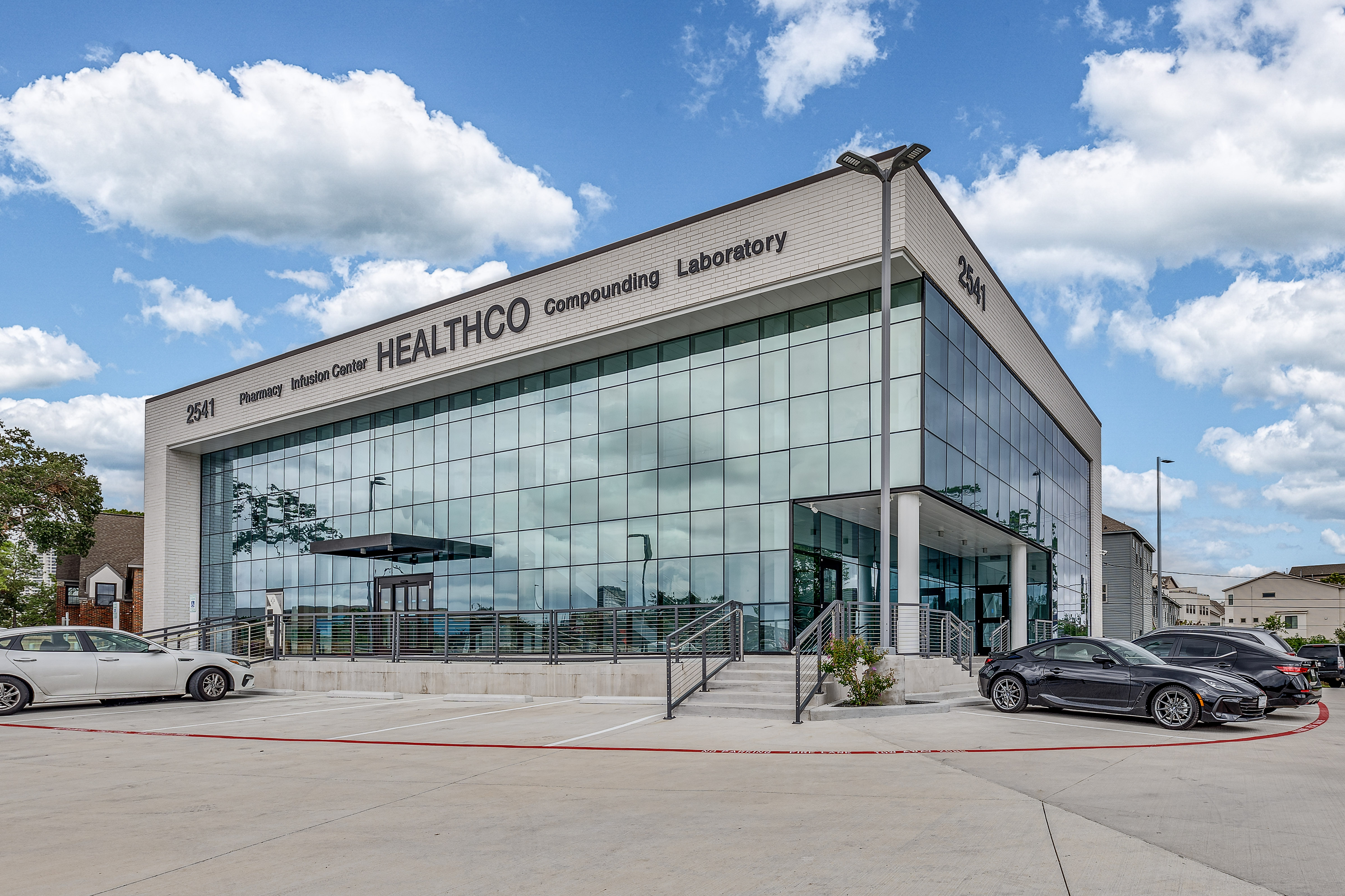 The HealthCo Pharmacy building in Houston — a modern glass-front facility housing the pharmacy, infusion center, compounding lab, and laboratory